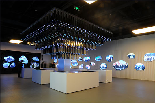 Exhibition space with illuminated overhead elements and wall displays